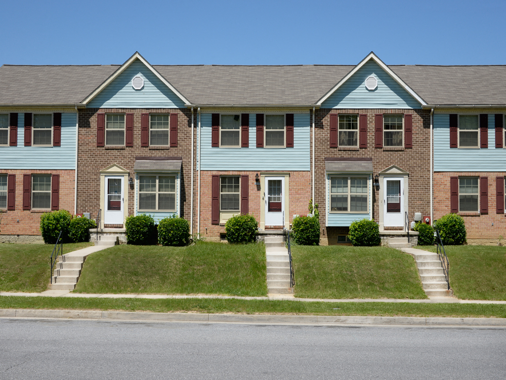 A blue and red brick house with a white door and windows.